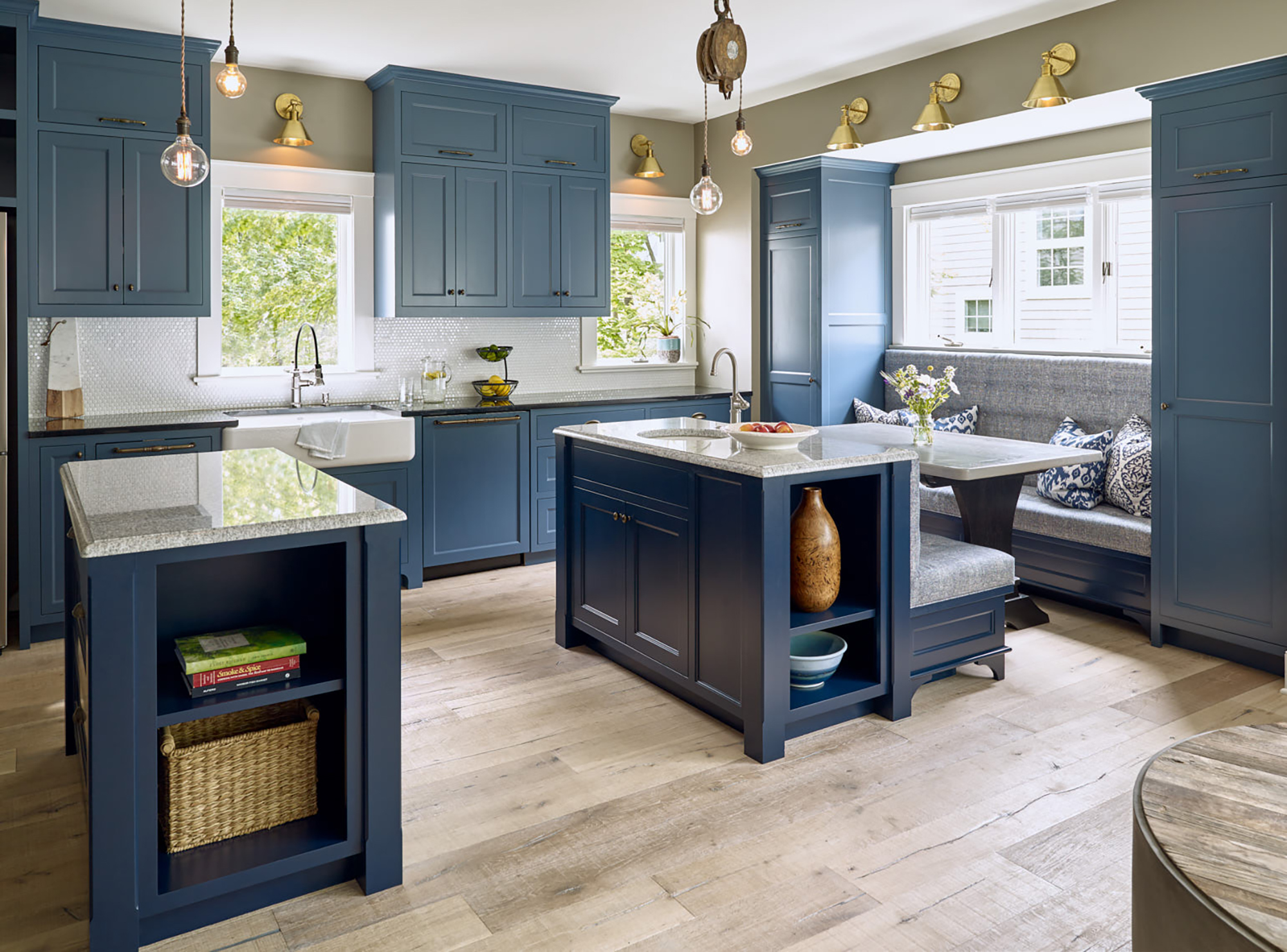 Large blue kitchen with built-in bench sitting areas and unique vintage lighting.