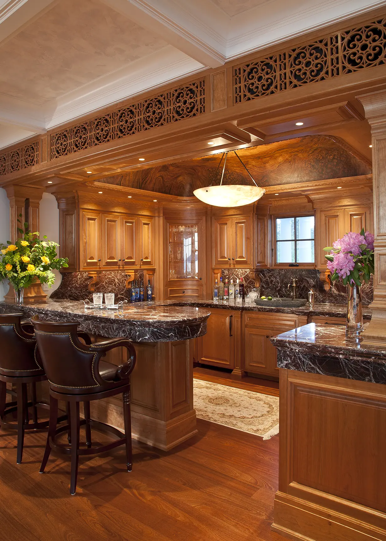 View of kitchen with ornate wood carvings and leather bar seats