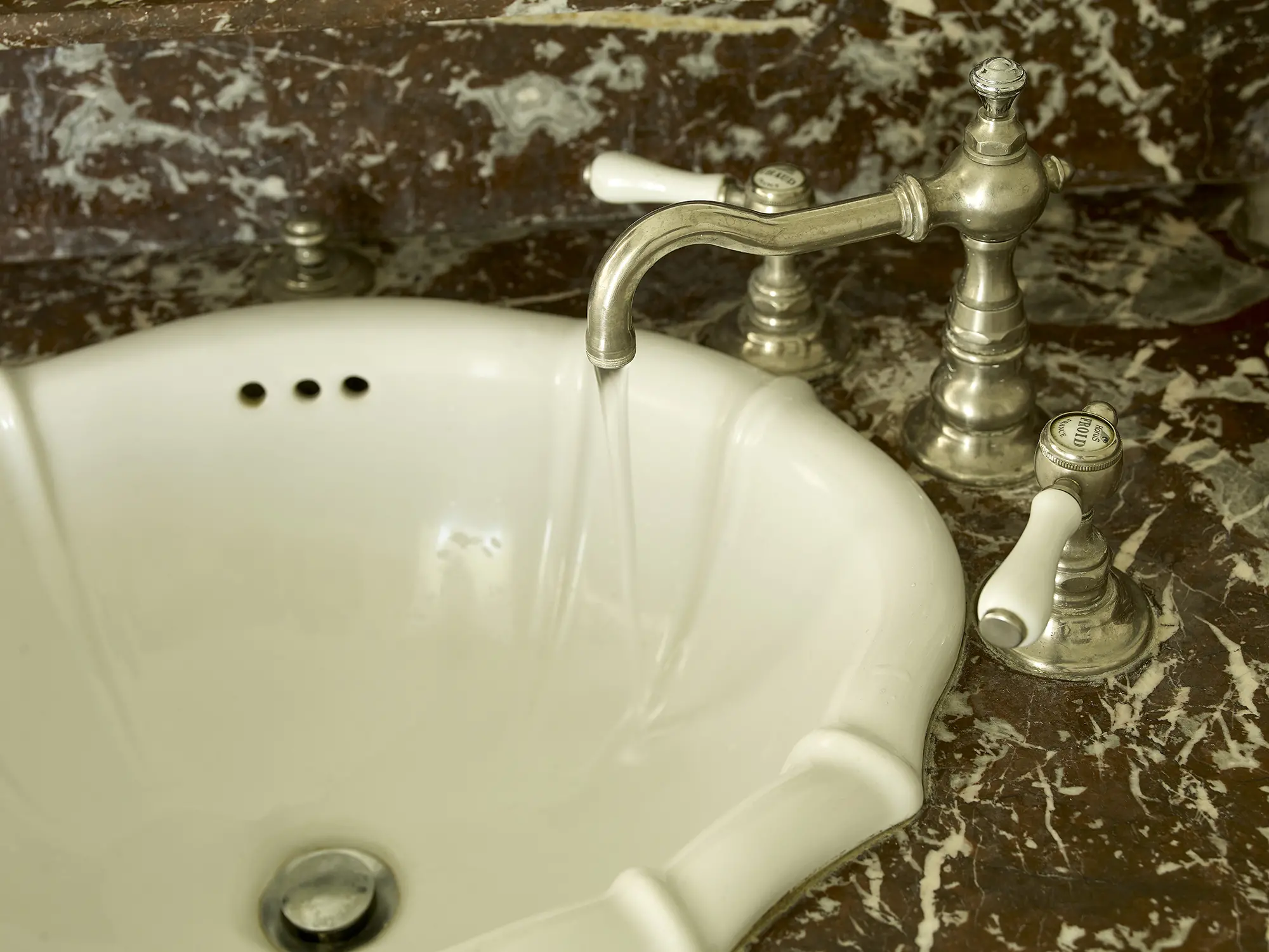 Detail of vintage porcelain sink and silver faucet