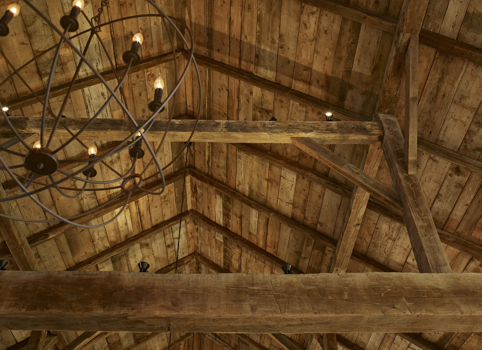 View of ceiling showing old wood beams and iron lighting fixture