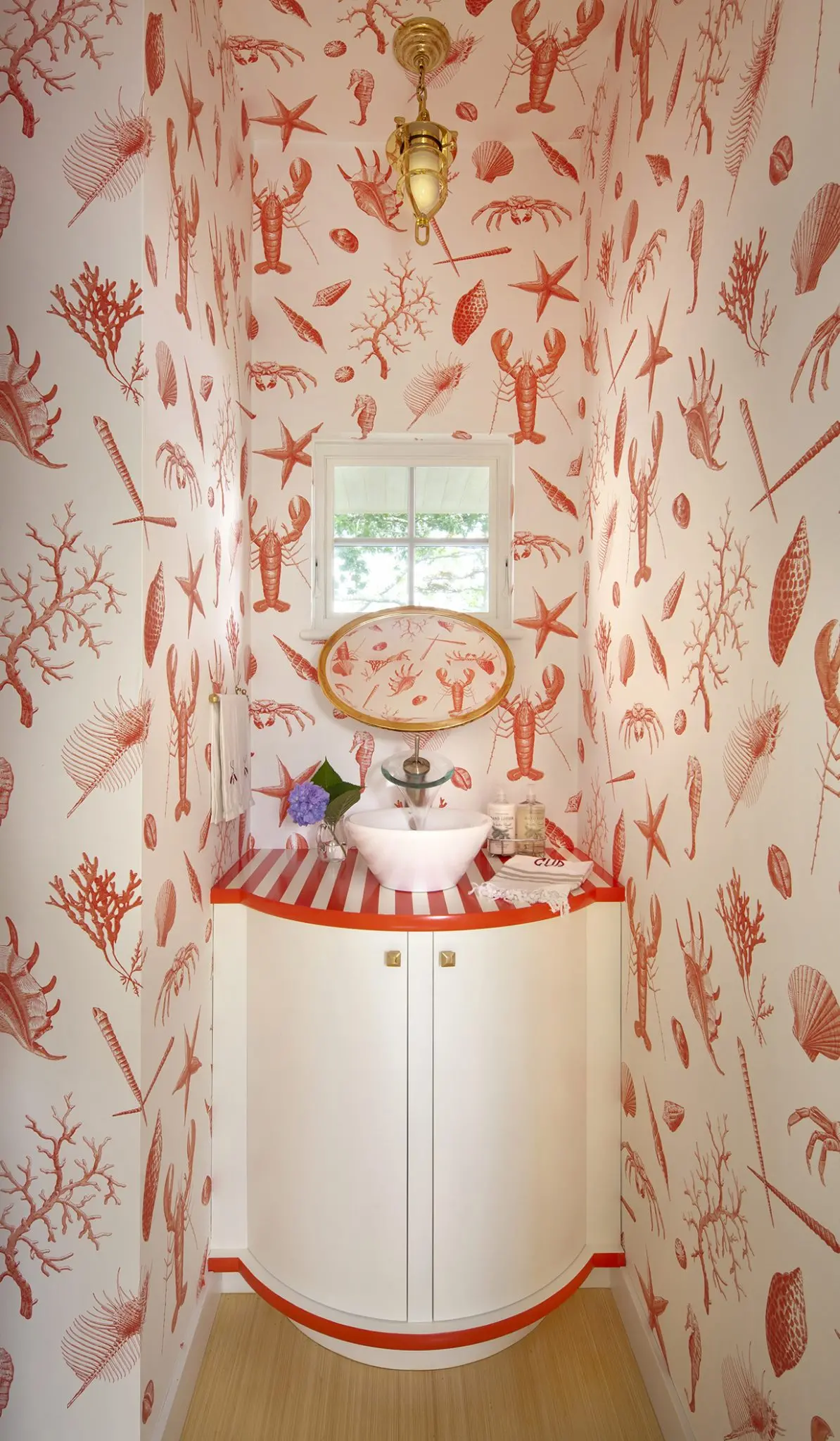 Marine life red wallpaper with lobsters, shellfish, coral, and more in the powder room at Ocean Ciff