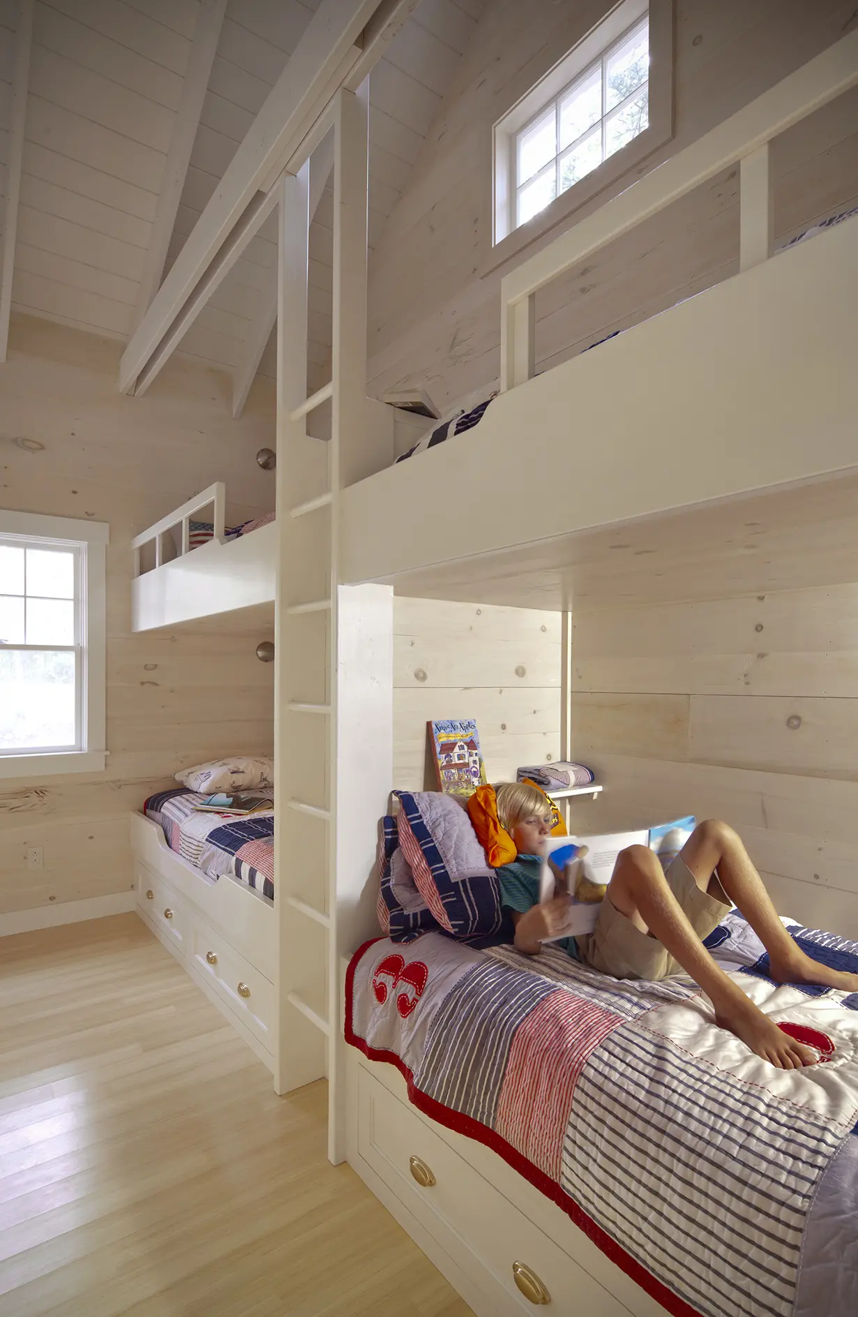 Bright and cozy bunk room with built-in bunkbeds and ladder.