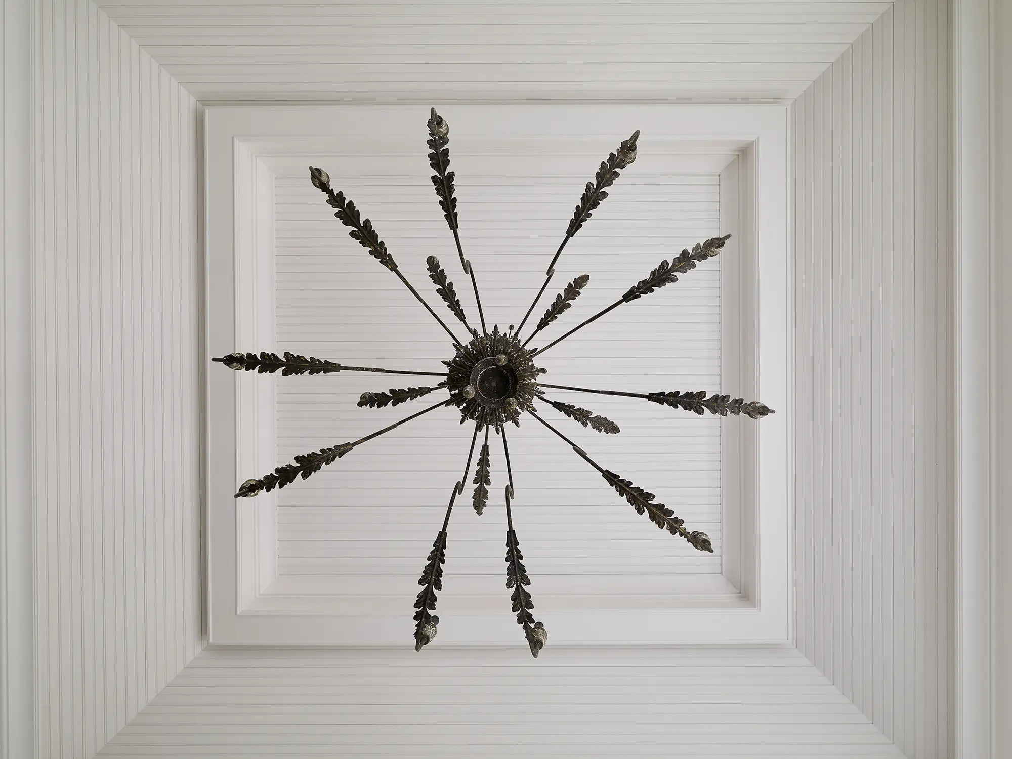 A unique metal feathered chandelier with white shiplap ceiling