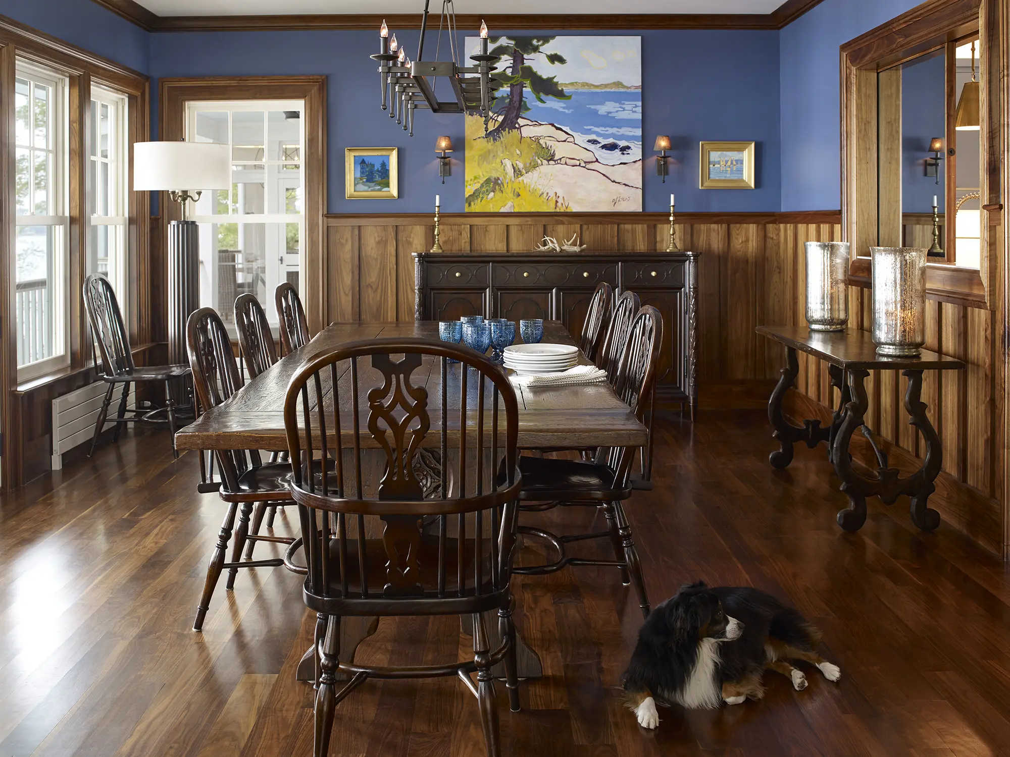 Dark wood dinning room with wood paneling and molding, complete with brass chandelier