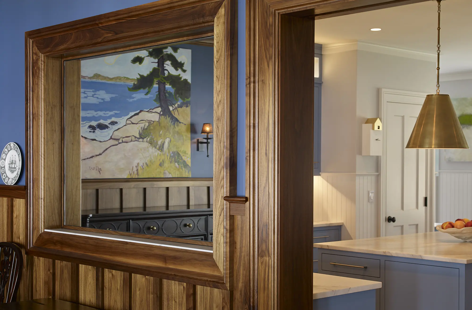 Wood window with mirror and door frame with view of periwinkle kitchen and gold light