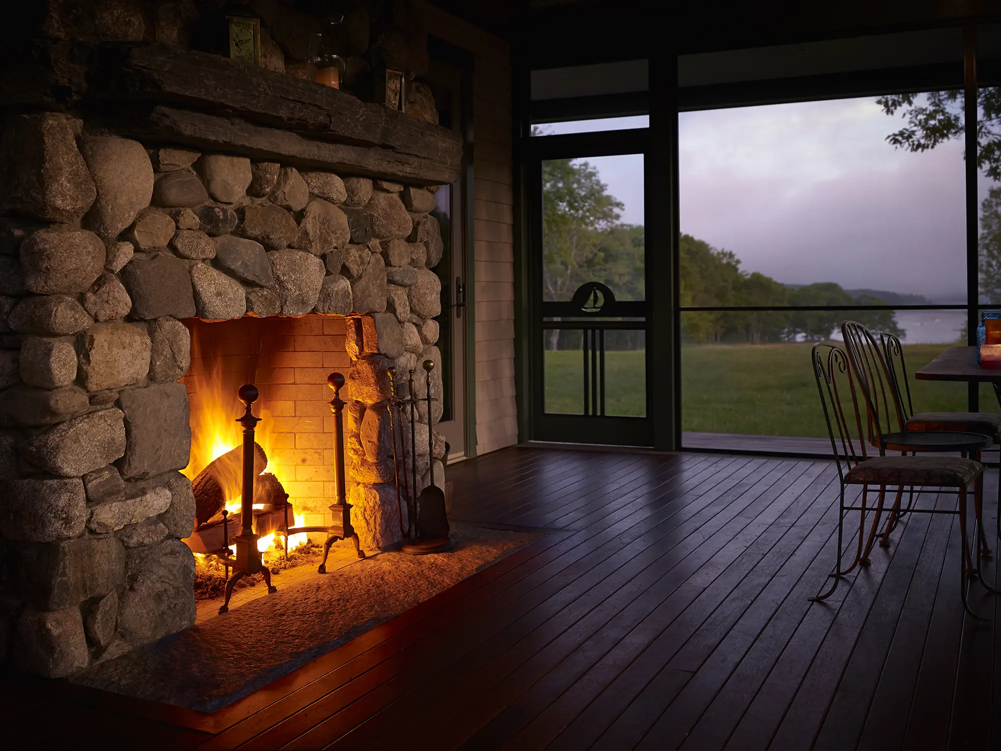Cozy stone fireplace at night with water views at Highfields