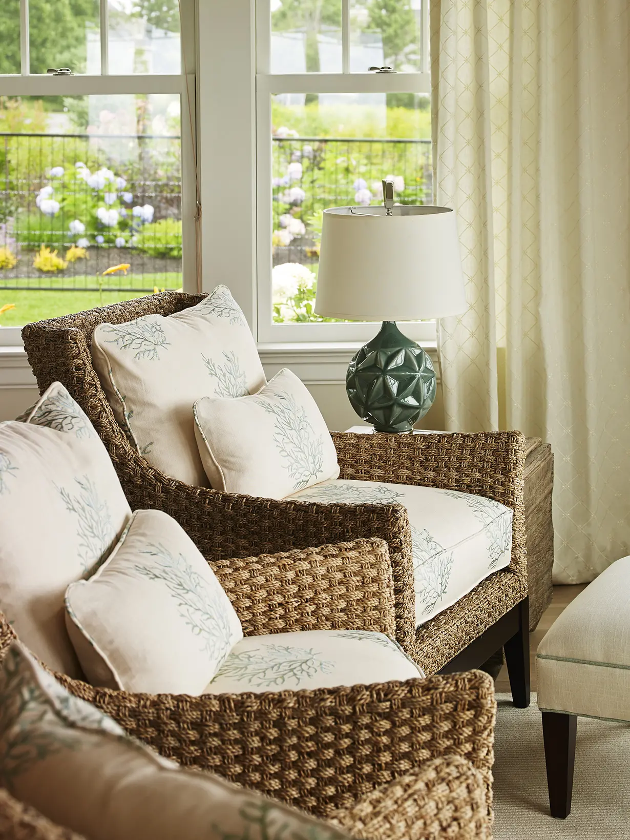 Woven chairs with coral cushions and statement lamp