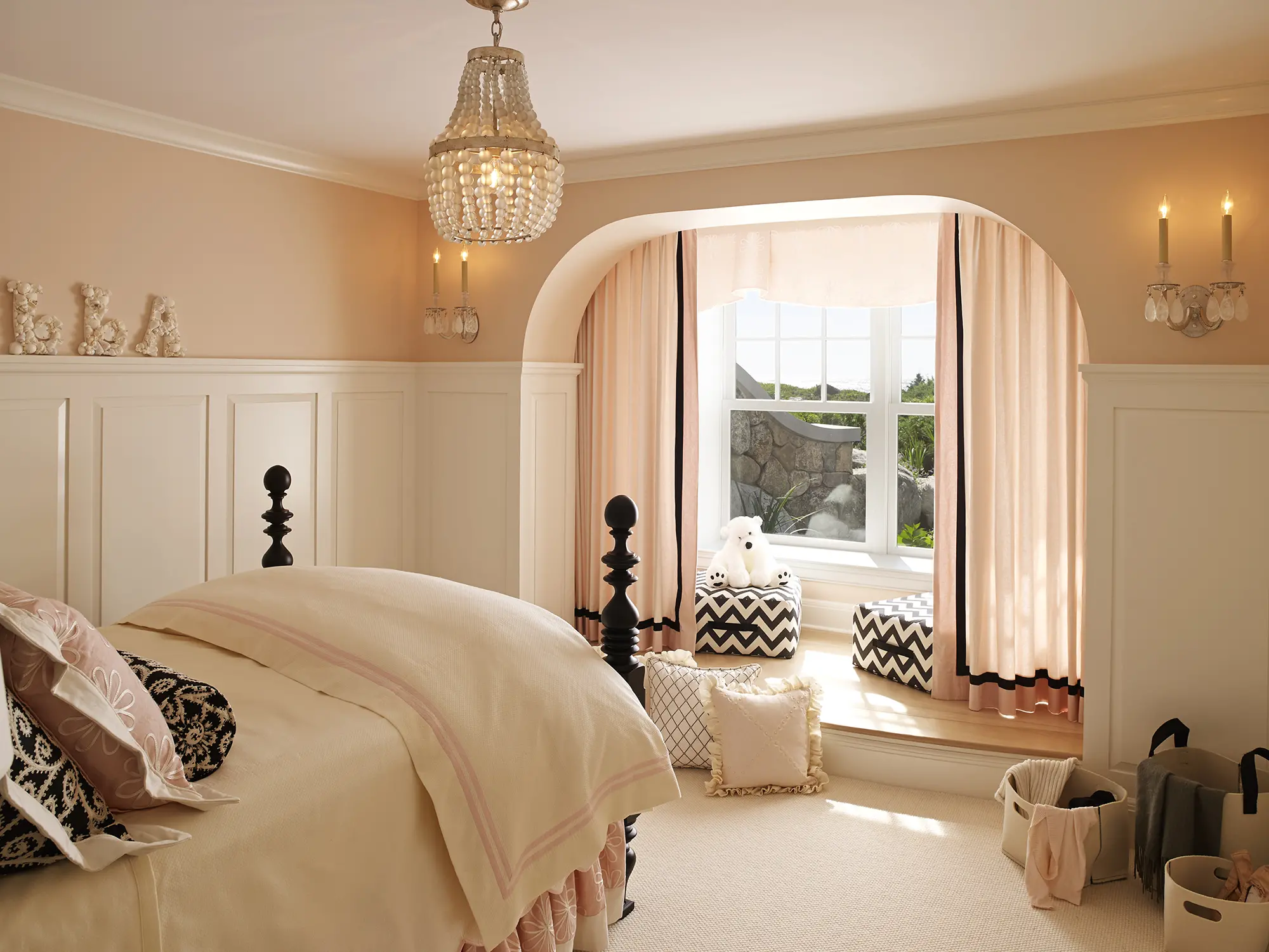Blush pink room with view of ocean and matching sconces and chandelier