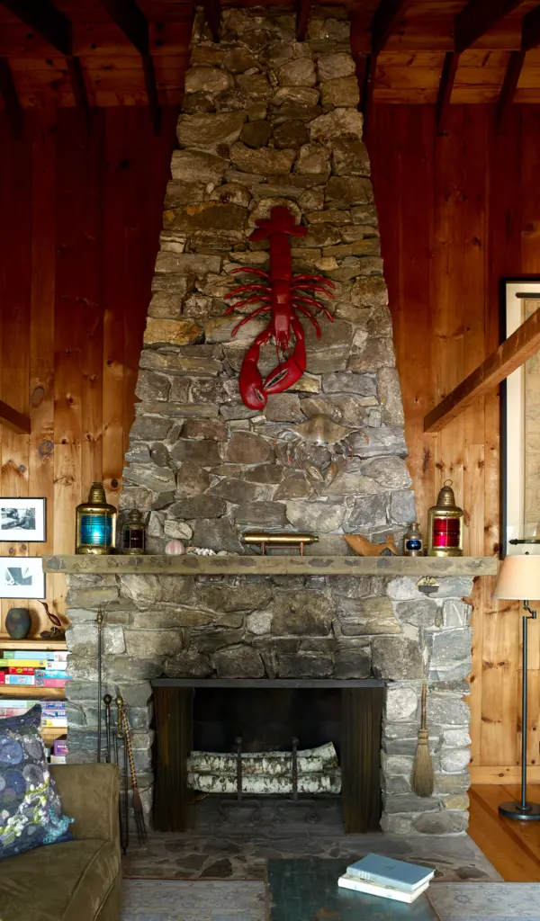 Tall stone fireplace with lobster decor at Little Acorn Cottage