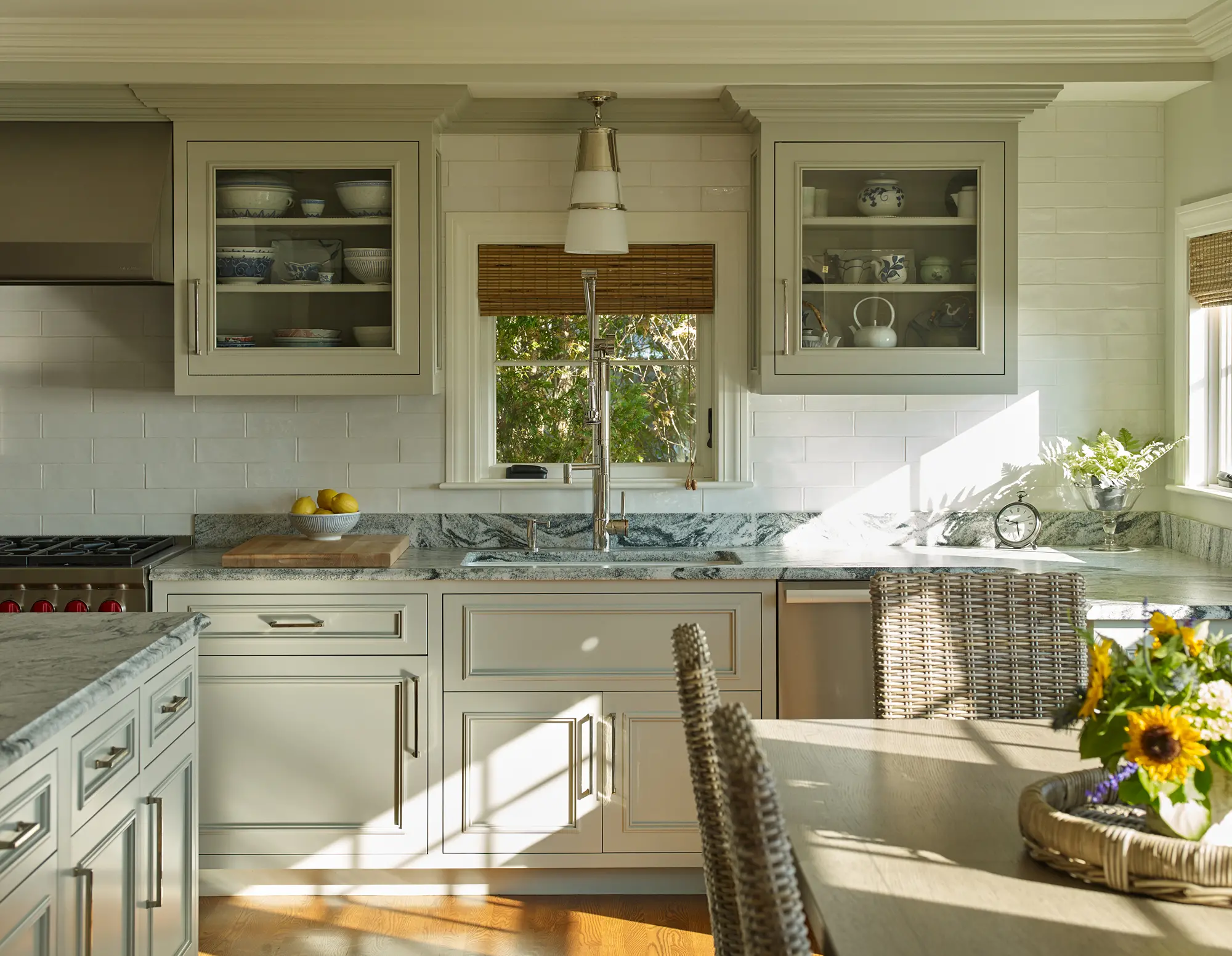 Cabinets with glass doors, marbled countertops, a large faucet and detailed molding.
