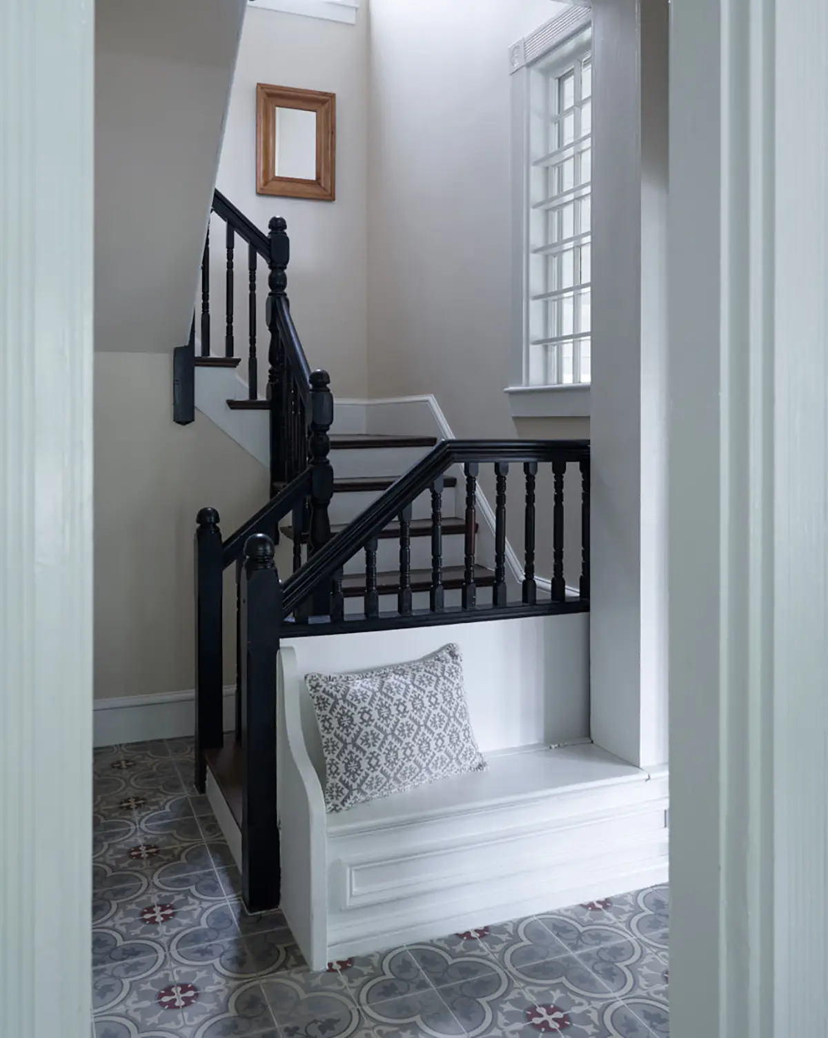 Built in bench with hidden storage at the bottom of the stairs at Casino Cottage with decorative tile