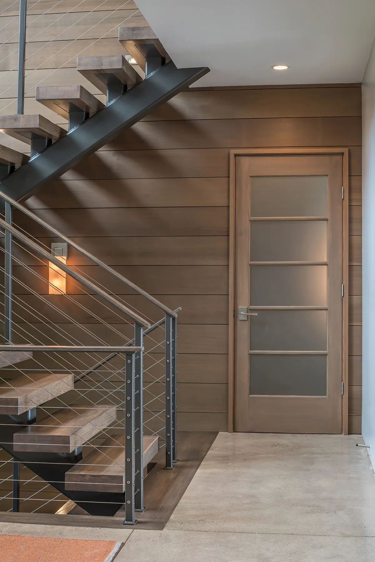 The contemporary staircase with the cabin-style paneled wall