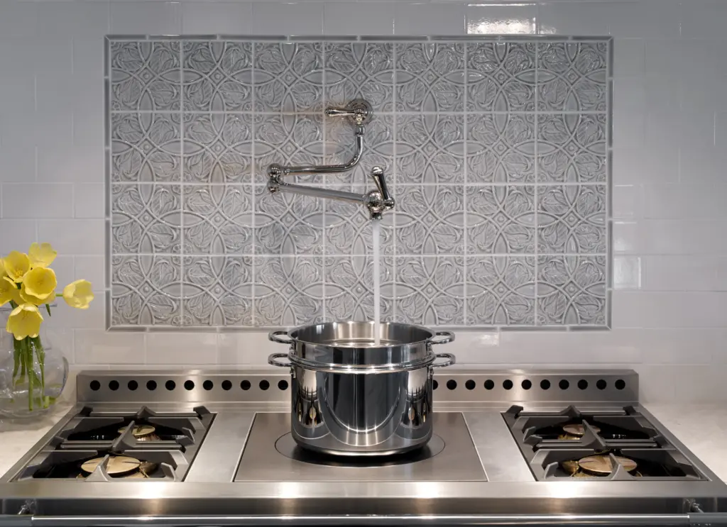 Unique tiled backsplash with a faucet over the stove.