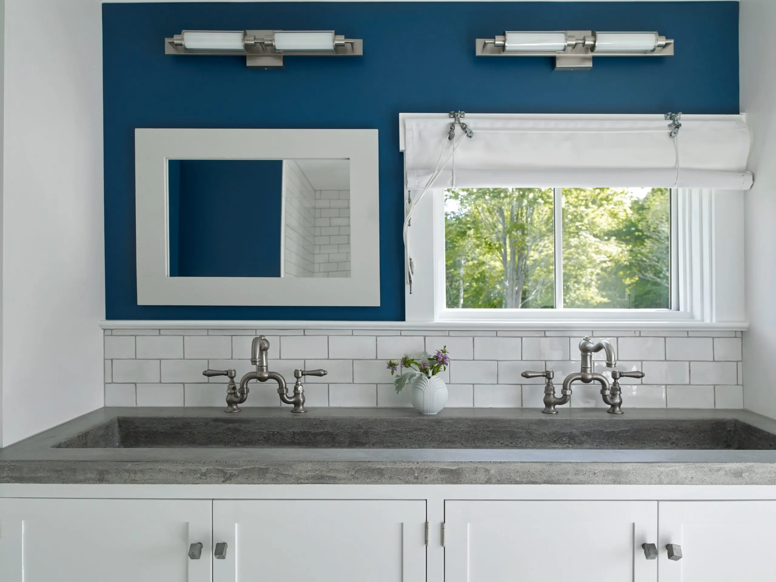 Double trough sink with beautiful contrast and navy blue accent wall.