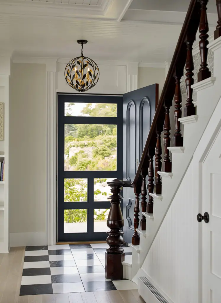 Beautiful staircase to entryway which features a unique light fixture, tile and wood flooring, and stunning contrast.