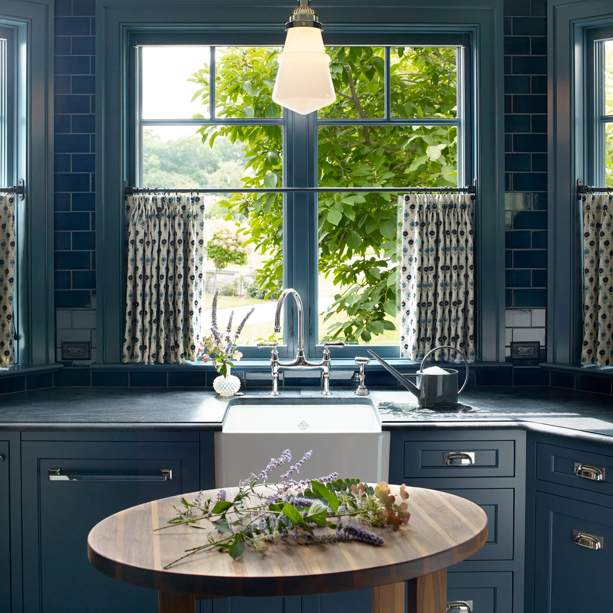 Blue tiled kitchen backsplash with farm sink and silver hardware
